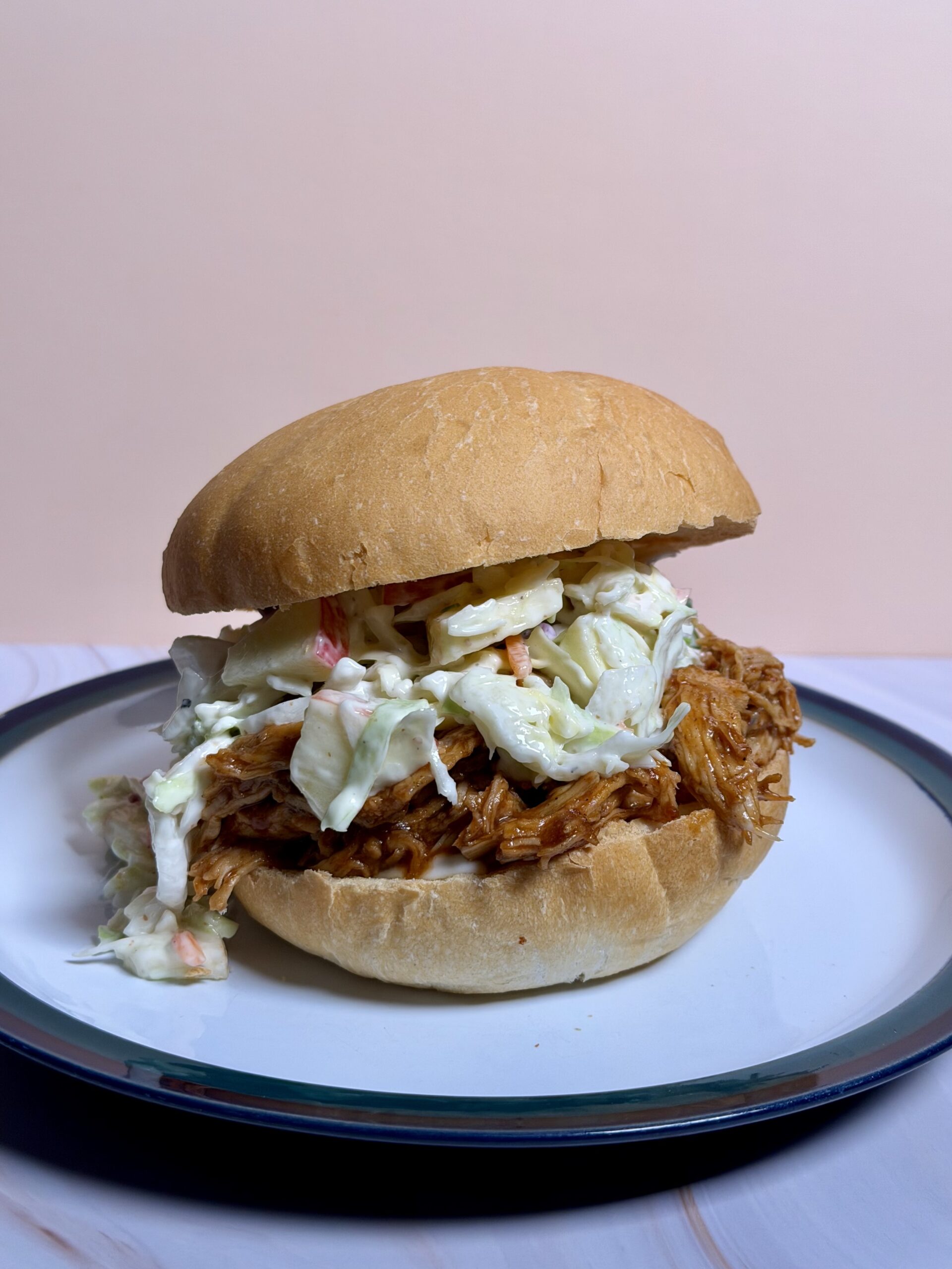 Pulled BBQ chicken sandwich topped with creamy coleslaw on a soft bun