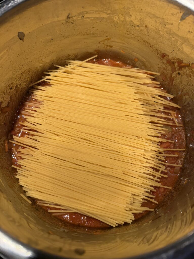 dry spaghetti noodles on top of sauce in instant pot