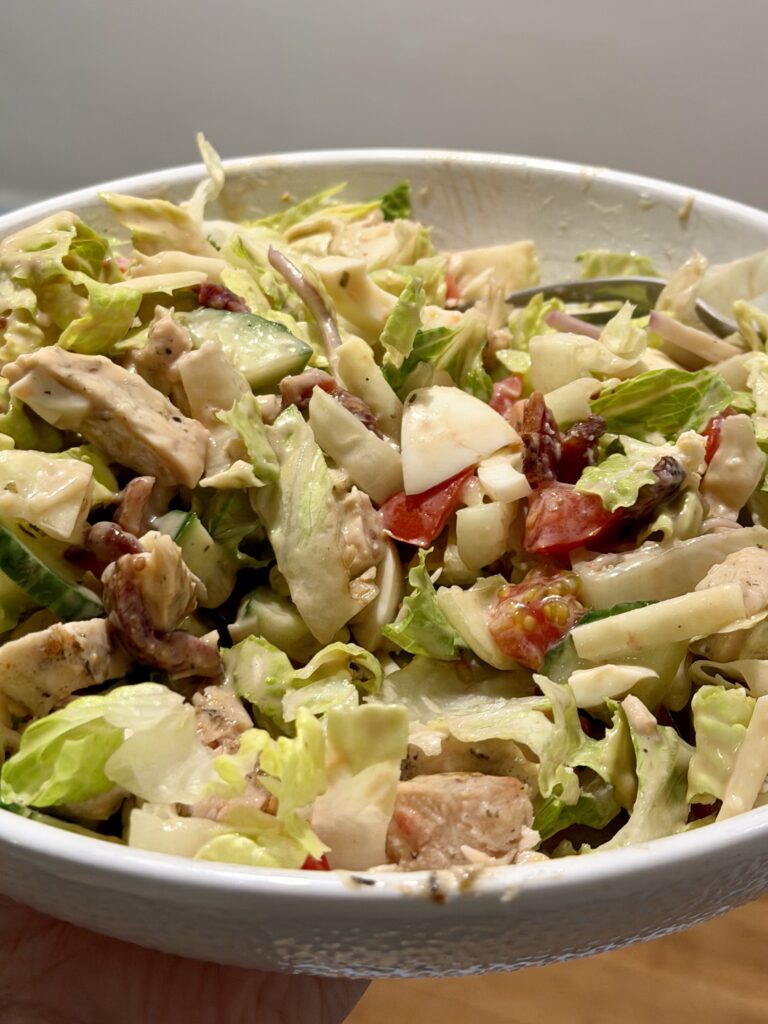 Mixed Cobb salad with chicken, vegetables, eggs, bacon, and creamy balsamic dressing