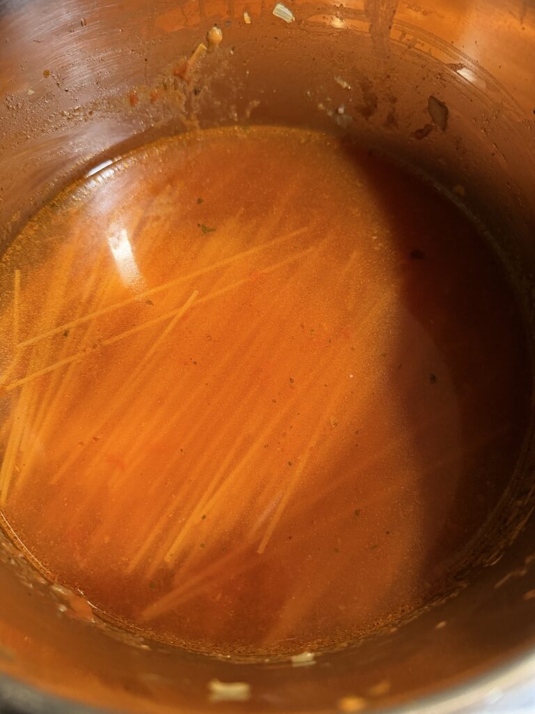water and sauce poured over uncooked spaghetti in instant pot